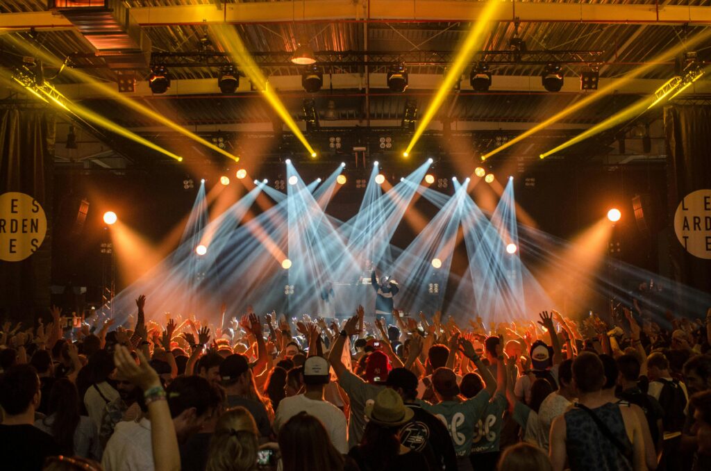 pexels-photo-167491-167491 Energetic music concert scene with bright lights and a lively cheering crowd indoors.